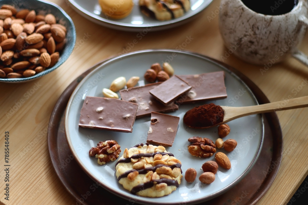 Cup of tea or coffee, cookies, macaroons, chocolate, various nuts and cocoa powder on wooden table. Selective focus. Cup of tea or coffee, cookies, macaroons, chocolate, various nuts and cocoa powder on wooden table. Selective focus.