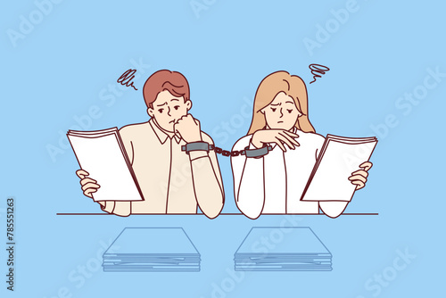 Paperwork forces handcuffed colleagues to do overtime, sitting at desk with papers. Problem of paperwork and excessive bureaucracy in corporations caused by lack of digitalization of work process