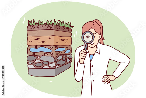 Woman scientist with magnifying glass is engaged in geology in search of deposits of valuable resources. Girl ecologist in white coat conducts examination of soil pollution