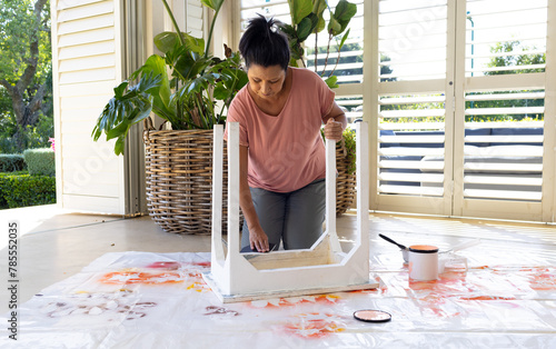 Mature biracial woman painting furniture at home in an upcycling project