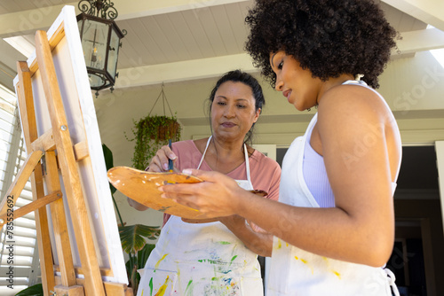 Mother and Daughter, mature biracial woman and young biracial woman painting together at home