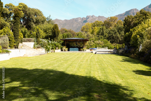Lush green lawn stretches towards gazebo with mountains in background at home