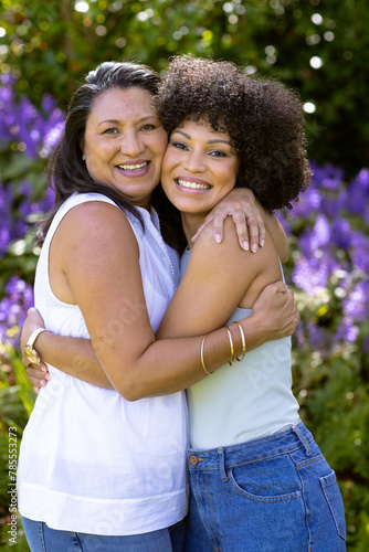 Mother and Daughter, mature biracial woman and young biracial woman embracing in garden at home