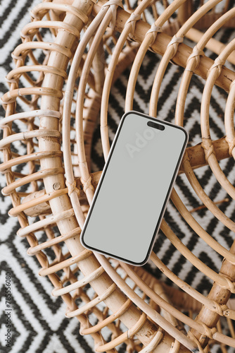 Flatlay mobile phone on ornamental bamboo table and carpet. Aesthetic elegant blog, online shopping, online store, social media branding mock up with blank copy space