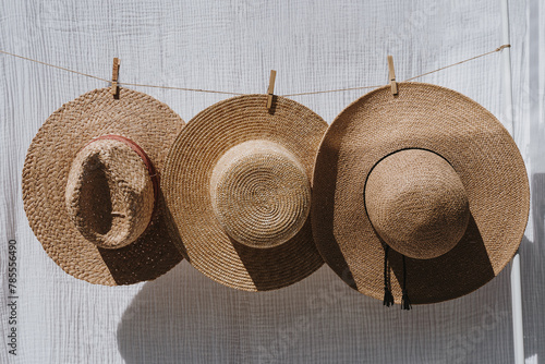 Three straw hats hanging over white cotton cloth with strong shadows. Sunbathing on a summer sunny day concept