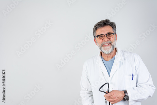Cheerful mature doctor posing and smiling at camera, healthcare and medicine. Smiling doctor posing with arms crossed in the office, he is wearing a stethoscope.
