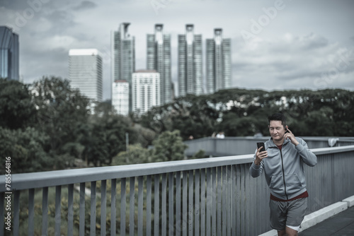 sport man running and listen music earphone and use smartphone Fitness application, social media, listening to music. Health and Lifestyle in big city life concept.