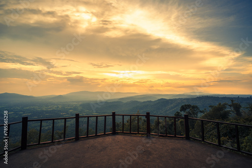 The wooden balcony has a view of the mountains and sunset behind.