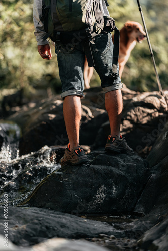 Hikers walk on rocks in the stream flowing from the waterfall..