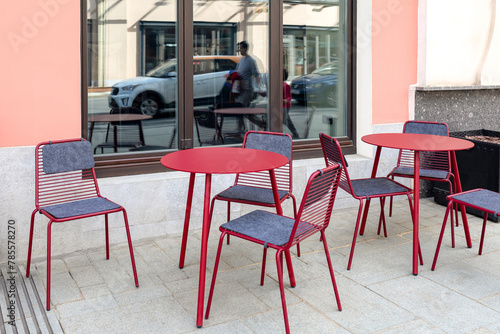 Empty street cafe. Red metal tables and chairs