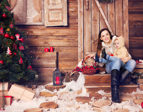 Stylish motherand her child celebrating christmas in room over christmas tree photo