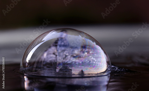 In einer Seifenblase auf einer Wasseroberfläche spiegelt sich die abendliche Landschaft