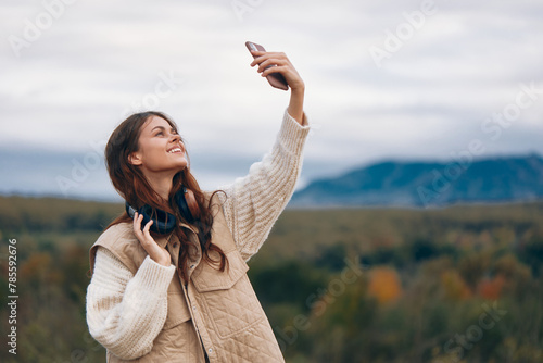 Mountain Adventures: A Smiling Woman Explores Nature and Captures a Selfie with Her Mobile Phone