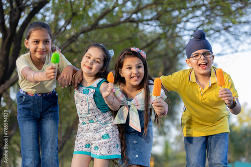 Group of kids having ice cream during summer camp .Kids having ice colorful ice candy enjoying summers