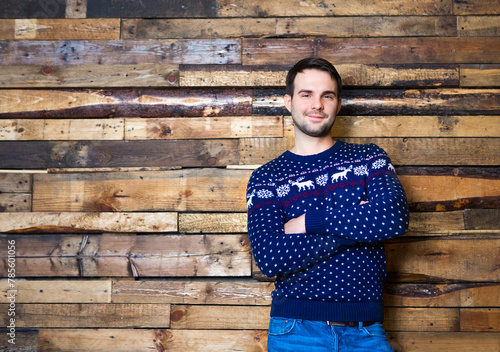 Happy man wearing Christmas sweater against wall background