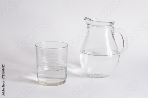 A  jug and a crystal glass containing water, isolated on a white background