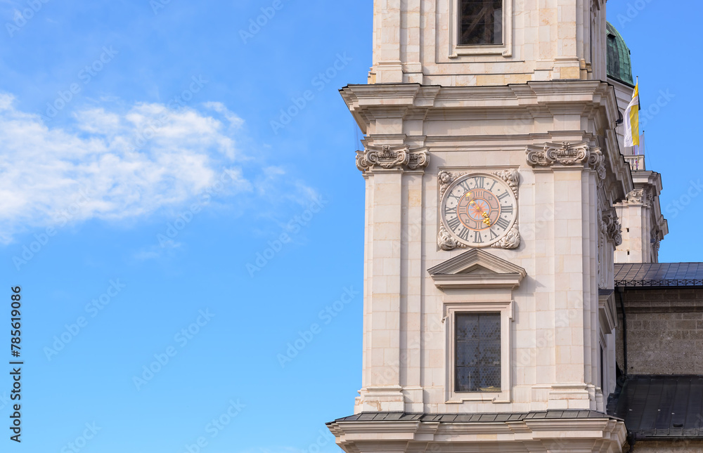 Part of the Salzburg Cathedral with a clock against a background of blue sky with cloud