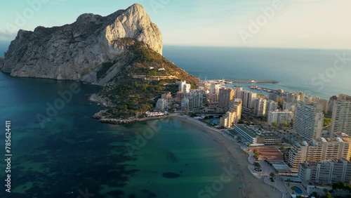 Aerial drone view of Calpe city at sunset. Warm colours reflecting on Penon de Ifach Mountain and buildings. Famous travel destination in province of Alicante, Valencian Community, Spain. Forward  photo