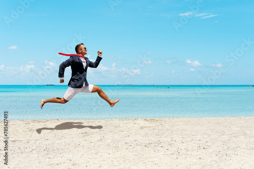 Happy businessman running away from office work on the beach.