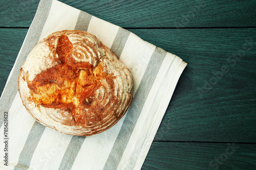 baked Italian bread on a green wooden table. ciabatta on a white towel on a wooden background	 photo