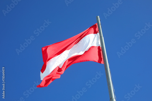 Austrian flag in white and red colors waving against a blue sky photo