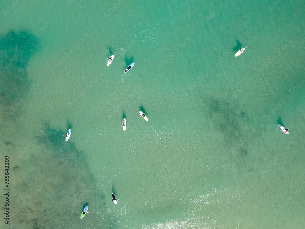 Aerial view by drone of people practicing Stand Up Paddle or SUP in Mediterranean turquoise clear sea.