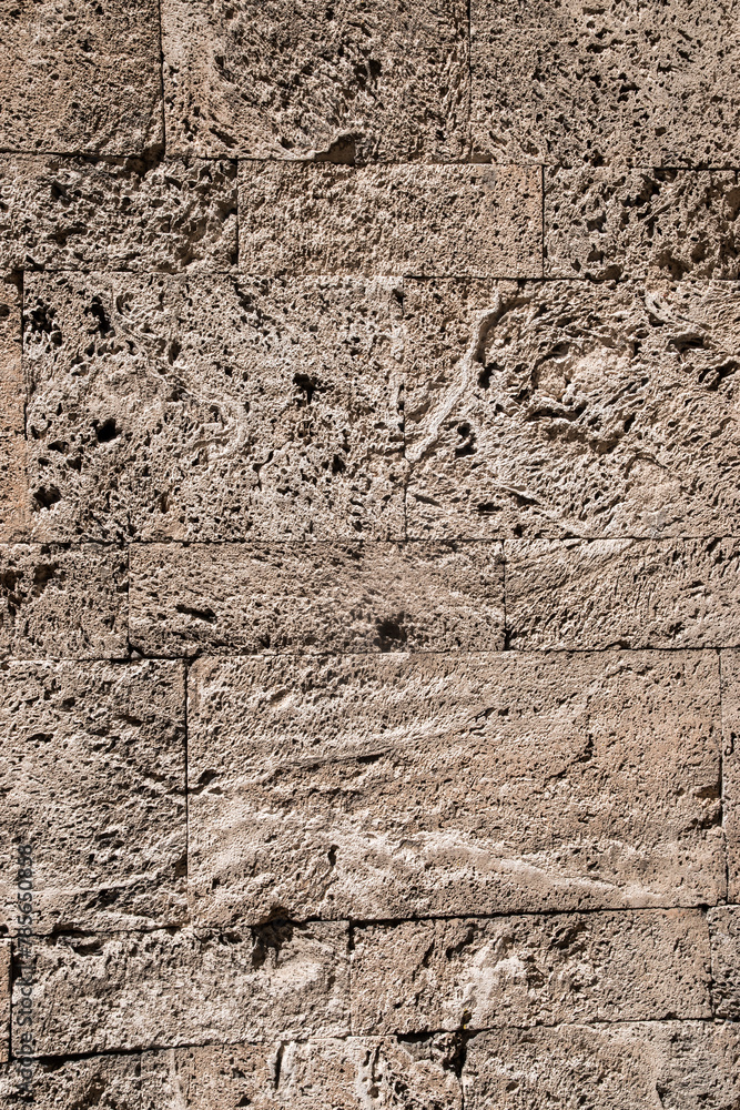 Stone wall of limestone bricks with spongy surface closeup as stone background Stone wall of limestone bricks with spongy surface closeup as stone background