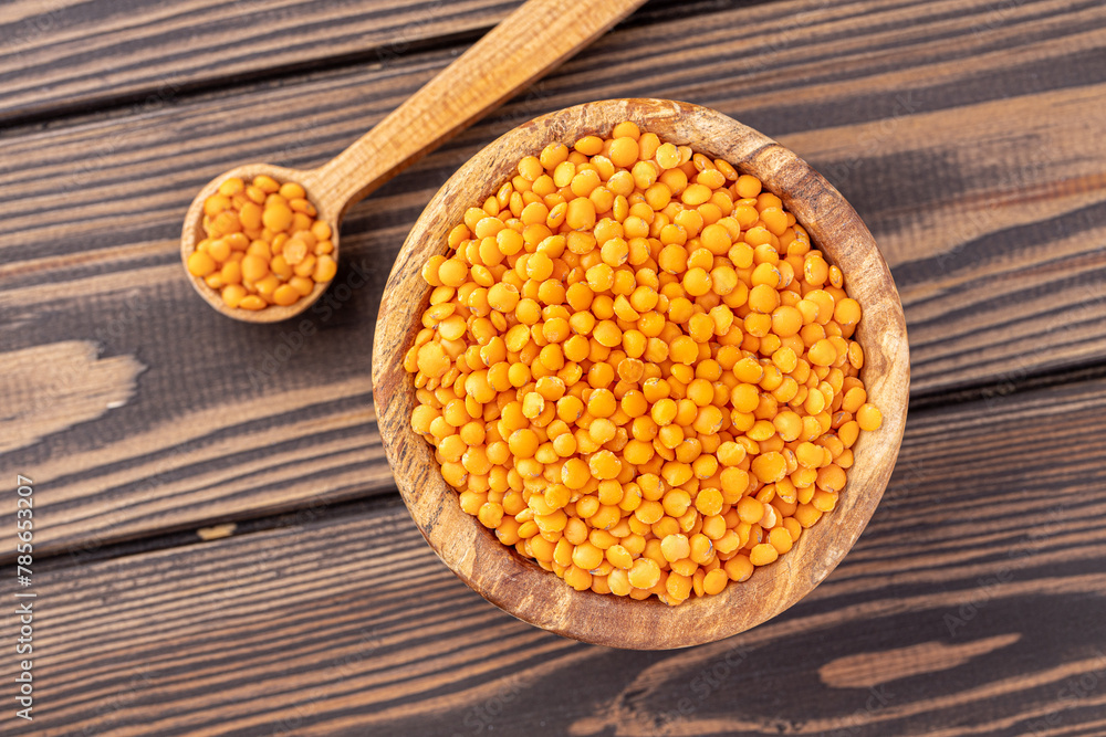 Photo of red lentils in wooden bowl with wooden measuring cup on wooden background. Healthy lifestyle. Vegetarian and vegan diet. Photo of red lentils in wooden bowl with wooden measuring cup on wooden background. Healthy lifestyle. Vegetarian and vegan diet.