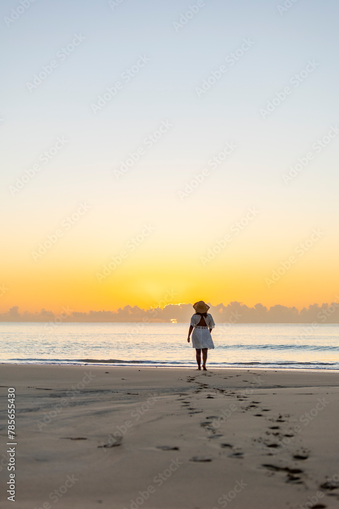 Woman enjoying a peaceful walk on the beach at sunrise Woman enjoying a peaceful walk on the beach at sunrise