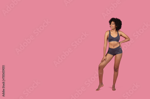 Standing African American lady in sportswear on pink background