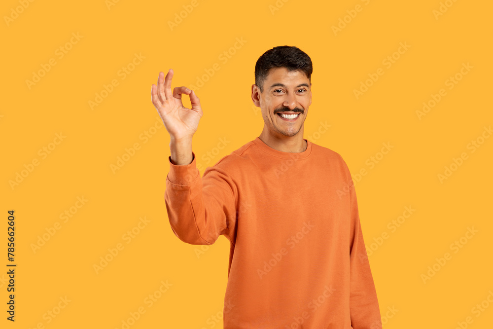 Joyful guy making OK gesture on orange Joyful guy making OK gesture on orange