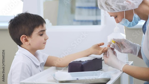 Doctor takes a patient's blood sample from a finger prick. Child's blood test. Blood test, blood group determination and medicine concept. Little boy in a hospital. photo