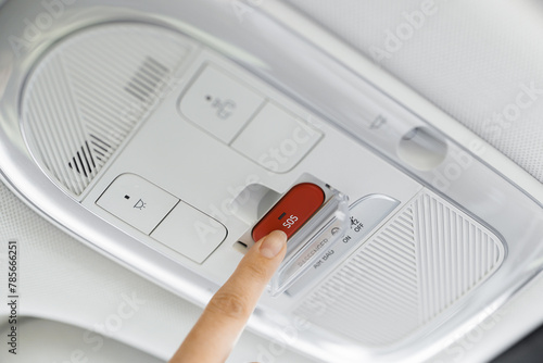 Finger pressing emergency sos button to contact with call center to ask for help after car accident. SOS button in a car as a symbol for the eCall system in European cars