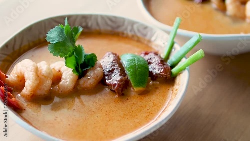 Tom yam kong ready-to-eat. Tom yum soup with shrimps on wooden table. Popular spicy Thai dish Tom Yam. Thailand food and Thai cuisine. Natural day light