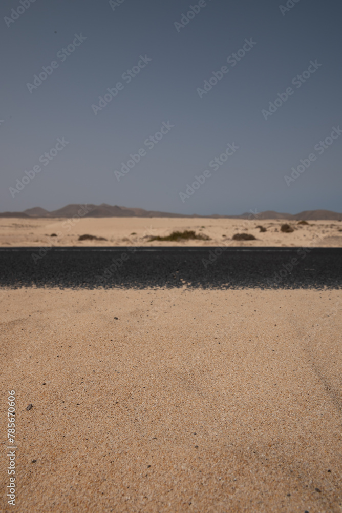 A desert landscape with a road in the middle. The road is empty and the sky is clear A desert landscape with a road in the middle. The road is empty and the sky is clear