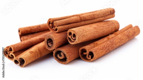 Cinnamon sticks are piledup on a white background.