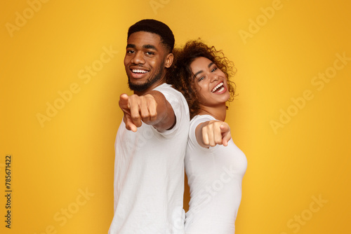 Joyful young couple pointing fingers at camera