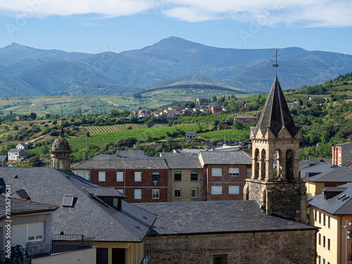 Vista del campanario de la Bas  lica de la Virgen de la Encina con el fondo de un paisaje de tejados y monta  as verdes con cielo azul en verano de 2021 en Le  n  Espa  a.