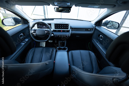 Electric car interior details adjustments. Inside car interior with front seats, driver and passenger, textile, windows, console, gear shift, electric buttons, digital speedometer, steering wheel.