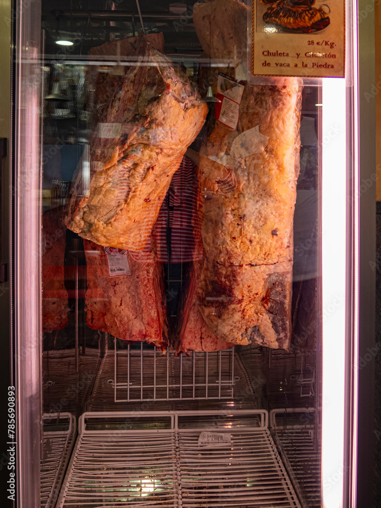Carne de ternera de máxima calidad colgada en un escaparate con luces rojizas, dentro de una nevera en un restaurante de Galicia, España 2021 - obrazy, fototapety, plakaty 