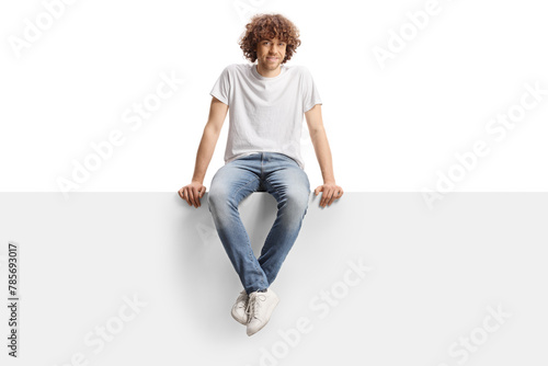 Cute guy with curly hair sitting on a blank panel