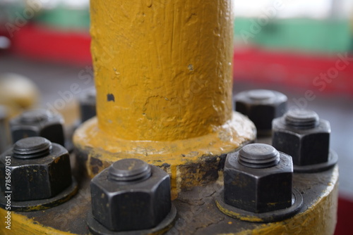 Close-up of a flange on a pipe carrying liquid to an industrial plant, with the bolts of a heavy metal joint.