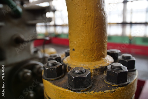 Close-up of a flange on a pipe carrying liquid to an industrial plant, with the bolts of a heavy metal joint.