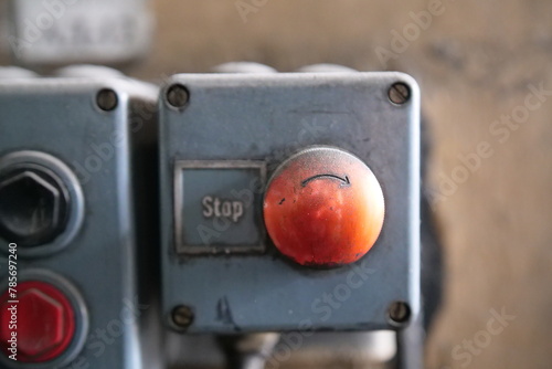 Selective focus on the red button of an industrial machine in front of a blurred background.