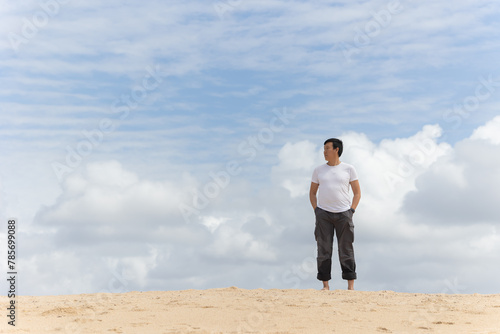 A man stands on a beach looking out at the ocean