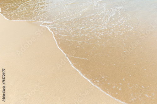 Small wave on a smooth sandy beach on a sunny day, viewed from above. Natural tropical travel, vacation and summer background with copy space.