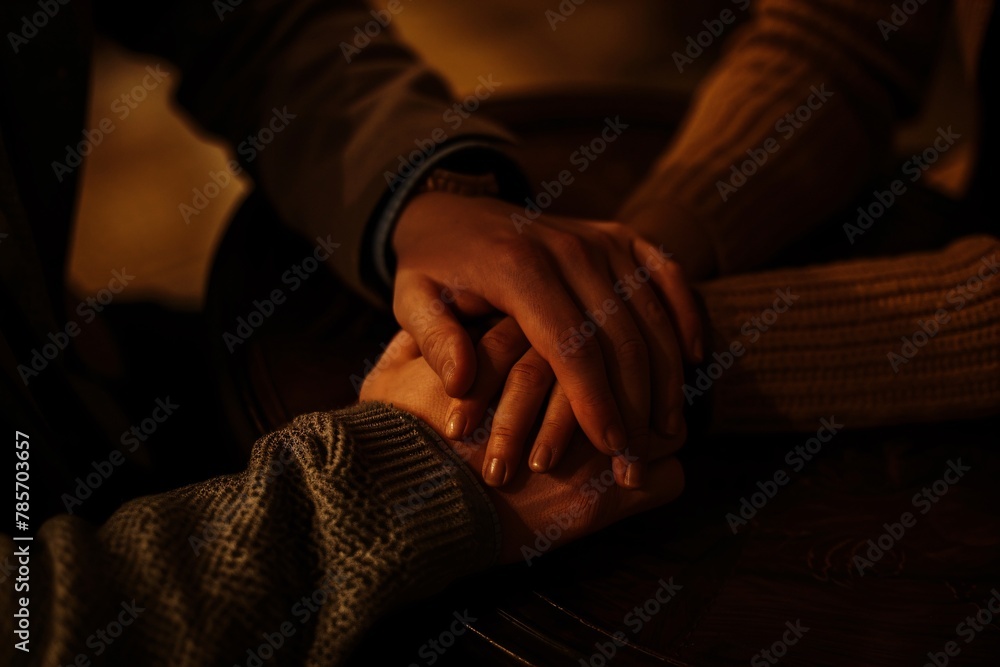 Close-up of a couple's clasped hands during divorce mediation, bathed in warm light, symbolizing their efforts to find closure.