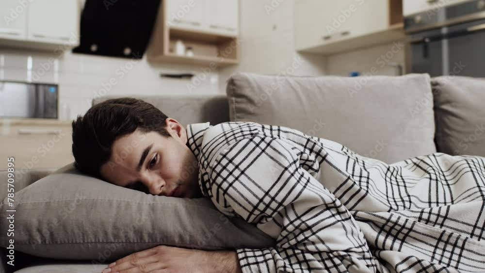Tired young caucasian man falling face down into a pillow on a couch at home after a hard work day. Concept of excessive fatigue because overtiming Tired young caucasian man falling face down into a pillow on a couch at home after a hard work day. Concept of excessive fatigue because overtiming