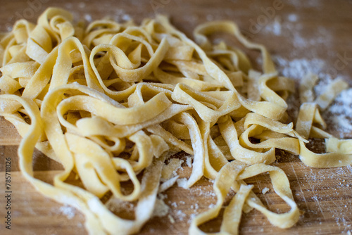 Pasta on a wooden background. Raw italian noodles tagliatelle on the wooden background.