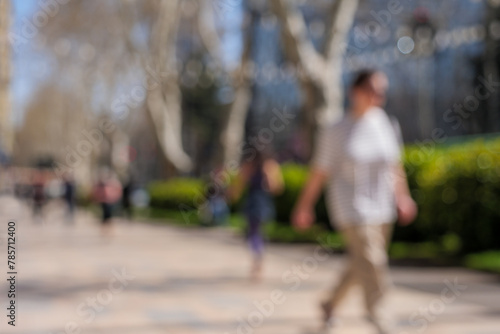Blurred photo of pedestrians walking on sidewalks on a sunny day. © Topuria Design